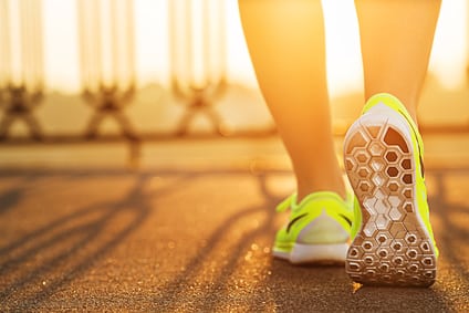 Runner woman feet running on road closeup on shoe. Female fitness model sunrise jog workout. Sports healthy lifestyle concept.