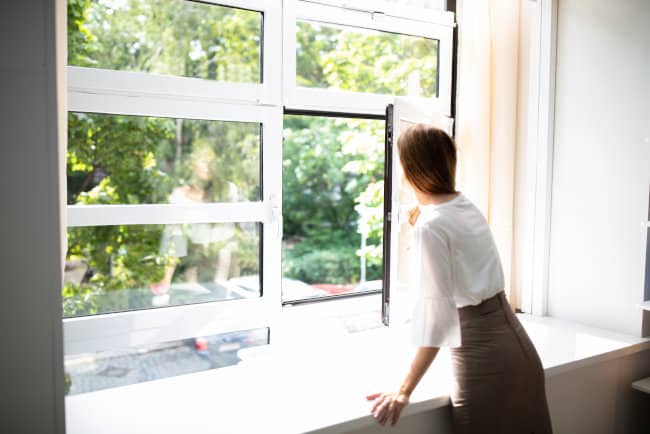 Side View Of A Businesswoman Looking Out Of A Window From An Office Building