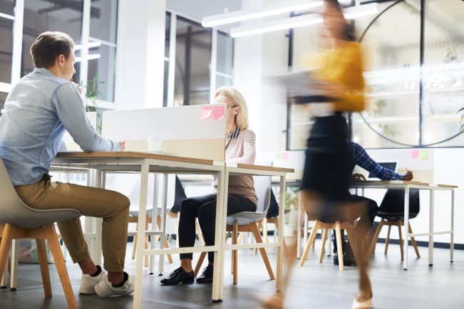 Work lifestyle in modern office: busy people working at tables in open space office, blurred motion of business lady